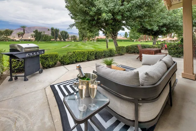 a view of a patio with table and chairs potted plants and large tree