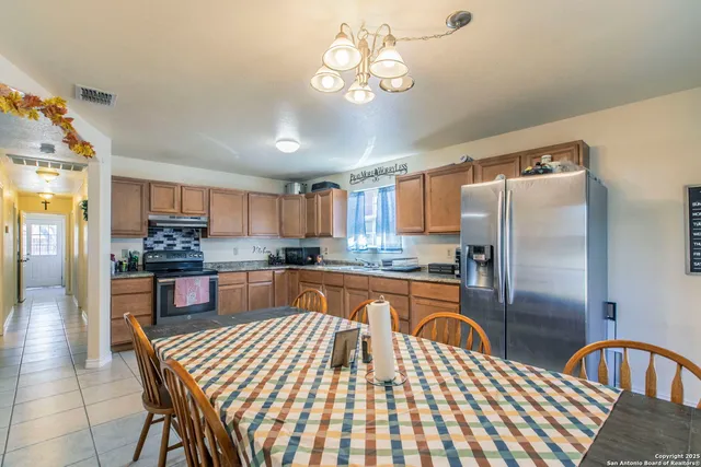 a kitchen with stainless steel appliances granite countertop a sink dishwasher a refrigerator with wooden cabinets and floor