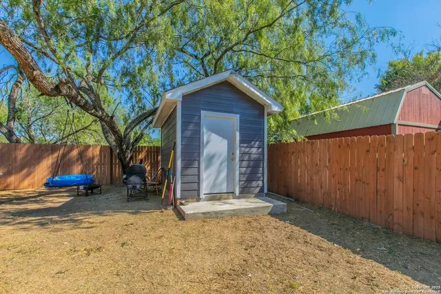 a view of a house with wooden fence and a large tree