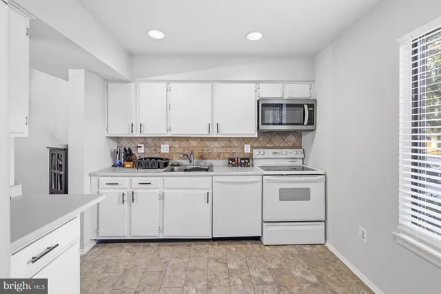 a kitchen with granite countertop white cabinets and white appliances