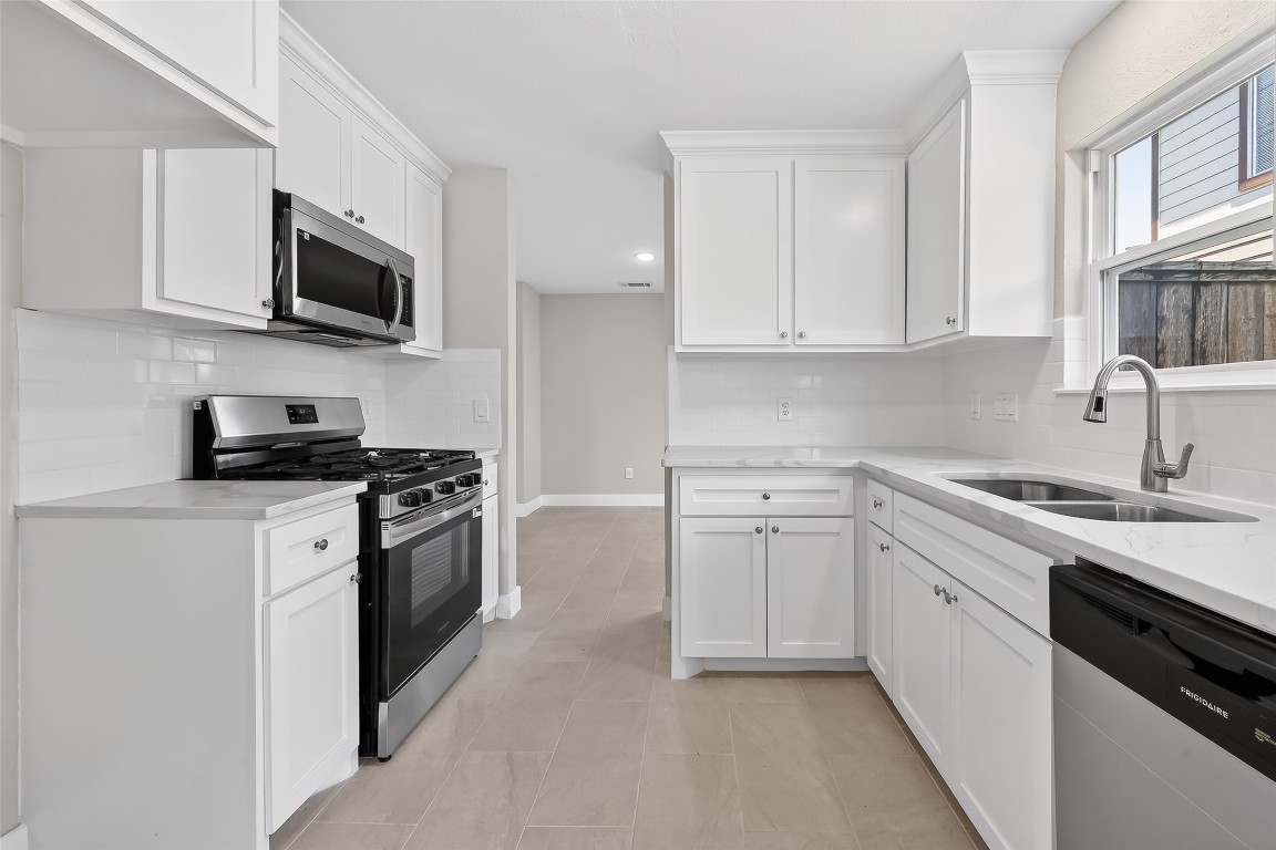 2318 Irish Spring Drive Houston, TX 77067 - Photo 8 of 25 a kitchen with stainless steel appliances a sink dishwasher a stove and a microwave oven on cabinets
