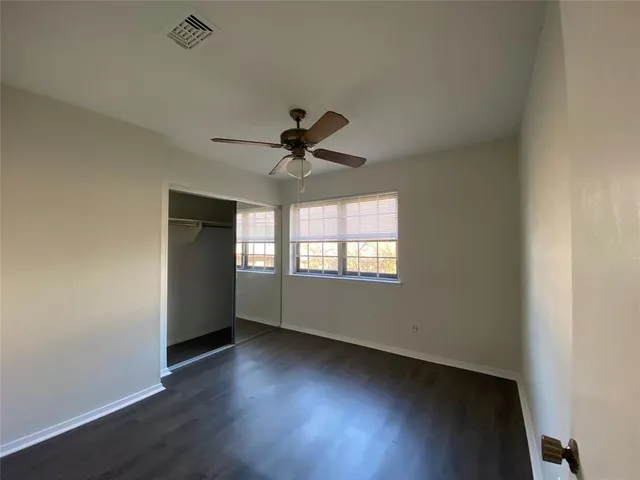 an empty room with wooden floor and ceiling fan