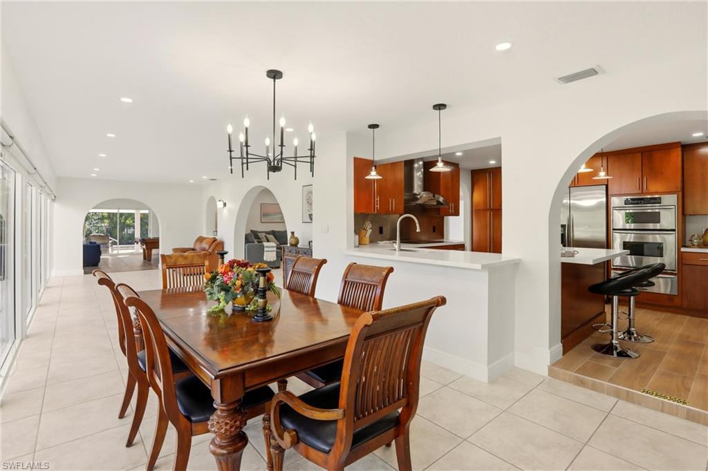 339 Landmark Street Marco Island, FL 34145 - Photo 18 of 50 Dining room with arched walkways, recessed lighting, a chandelier, and light tile patterned floors