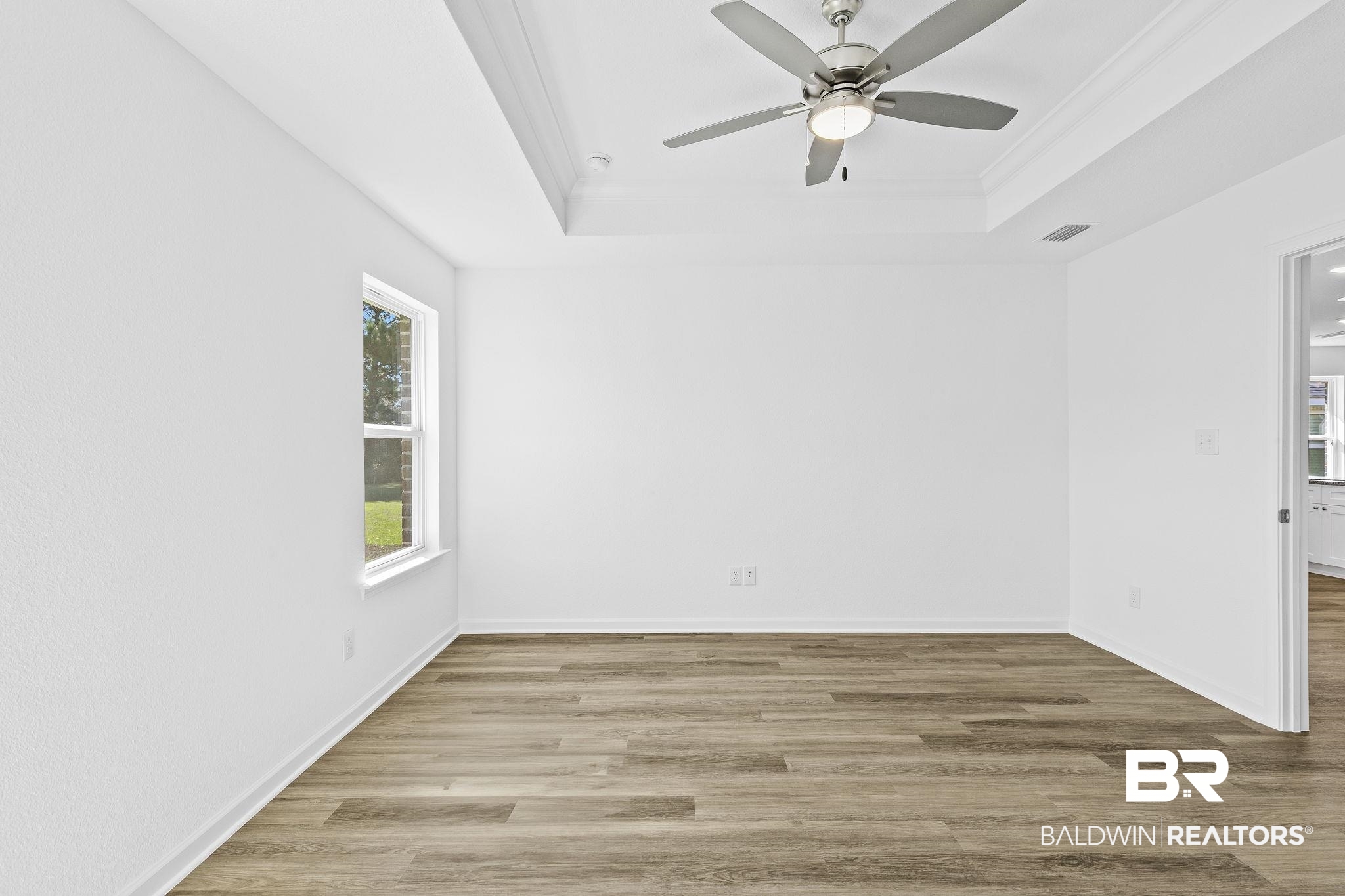 16014 Alabama Avenue Silverhill, AL 36576 - Photo 20 of 50 Spare room with wood-type flooring, crown molding, a tray ceiling, and ceiling fan