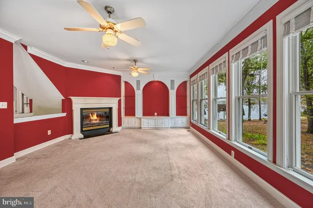 an empty room with windows and ceiling fan