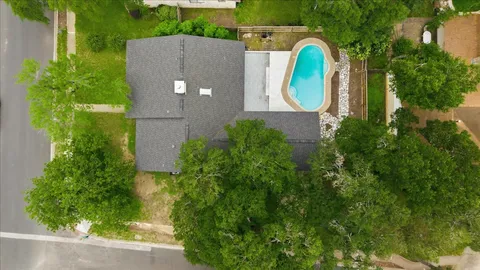 an aerial view of a house with a swimming pool and garden
