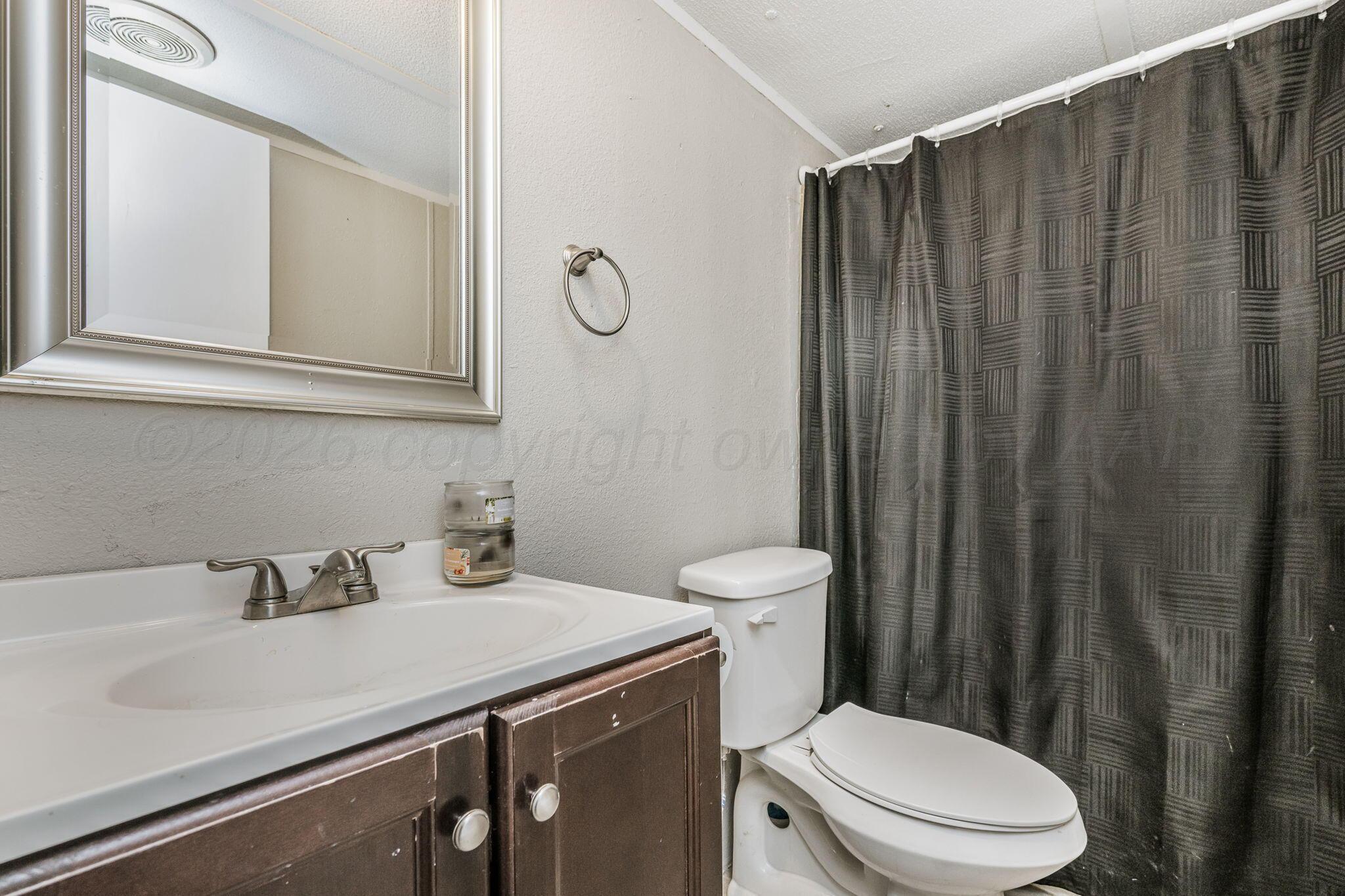 2115 Country Lane Amarillo, TX 79118 - Photo 14 of 15 a bathroom with a sink a toilet a mirror and shower curtain