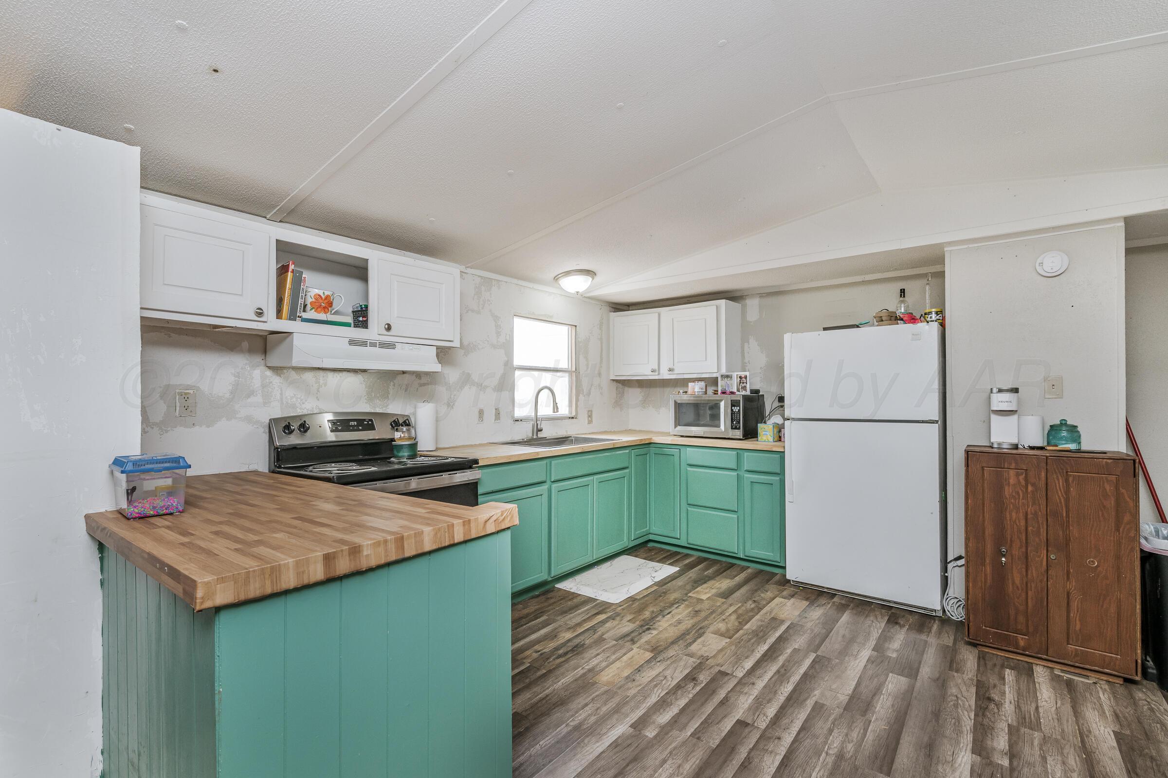 2115 Country Lane Amarillo, TX 79118 - Photo 3 of 15 a kitchen with a refrigerator a stove top oven a sink and cabinets
