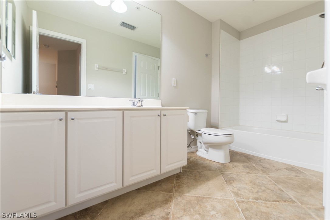 15633 Marcello Circle, Unit 133 Naples, FL 34110 - Photo 13 of 23 a spacious bathroom with a toilet sink and mirror
