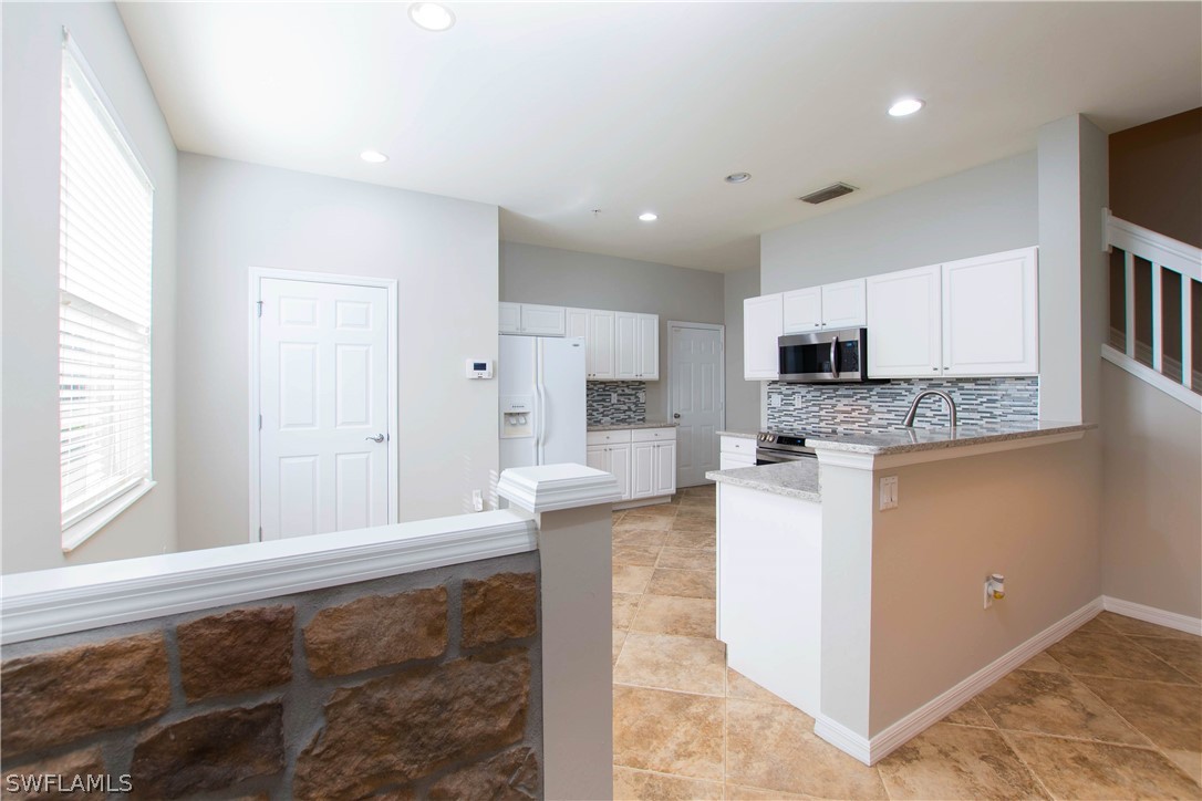15633 Marcello Circle, Unit 133 Naples, FL 34110 - Photo 4 of 23 a large white kitchen with cabinets