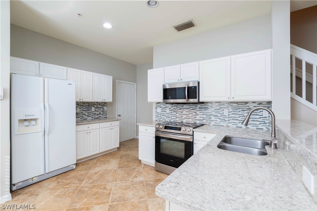 15633 Marcello Circle, Unit 133 Naples, FL 34110 - Photo 5 of 23 a kitchen with white cabinets and stainless steel appliances