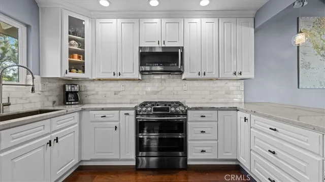 a kitchen with granite countertop white cabinets and stainless steel appliances