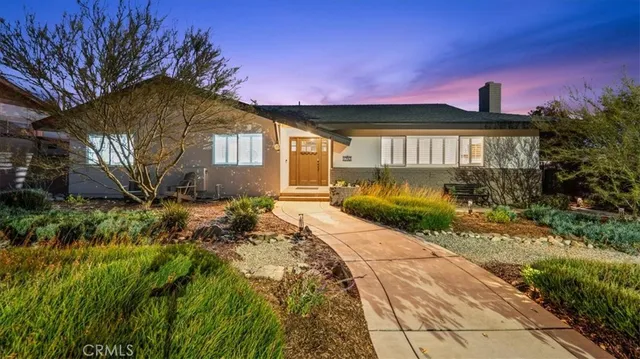 a front view of a house with a yard and potted plants
