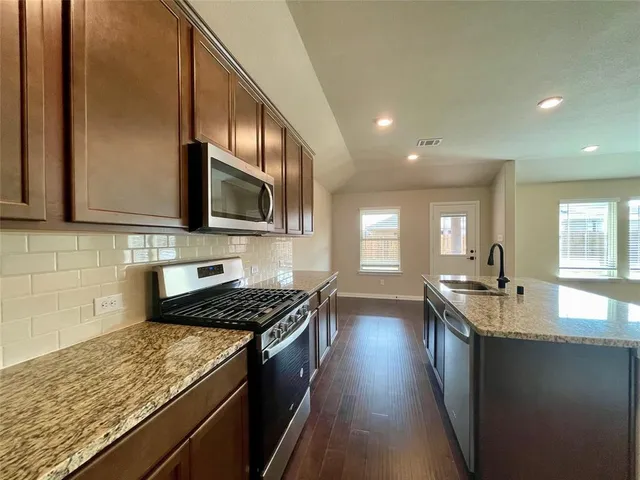 a kitchen with stainless steel appliances granite countertop a sink stove and microwave