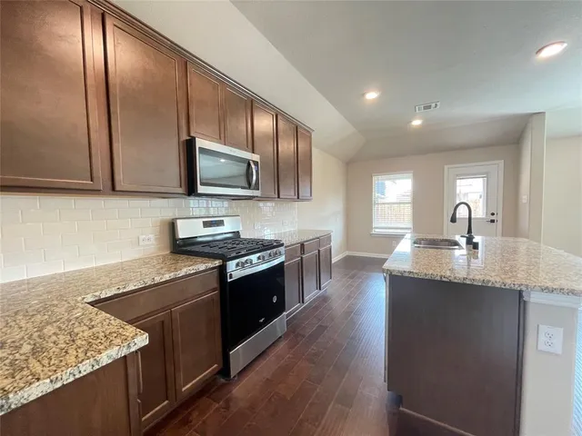 a kitchen with granite countertop stainless steel appliances and wooden cabinets