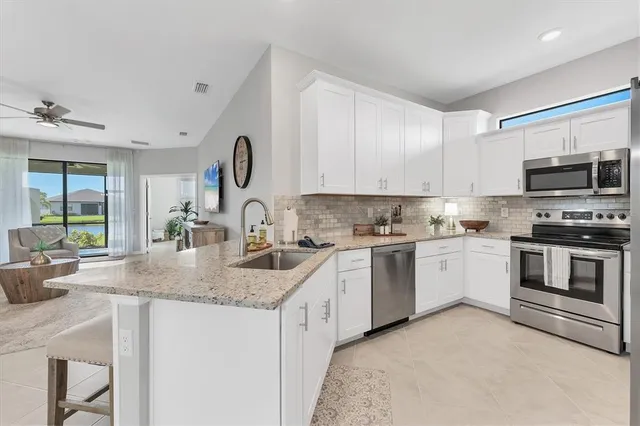 a kitchen with granite countertop a sink stainless steel appliances and white cabinets