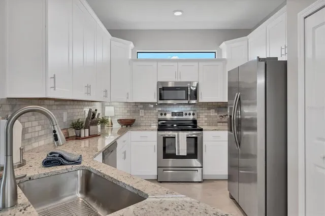 a kitchen with stainless steel appliances granite countertop a sink a stove a refrigerator and cabinets