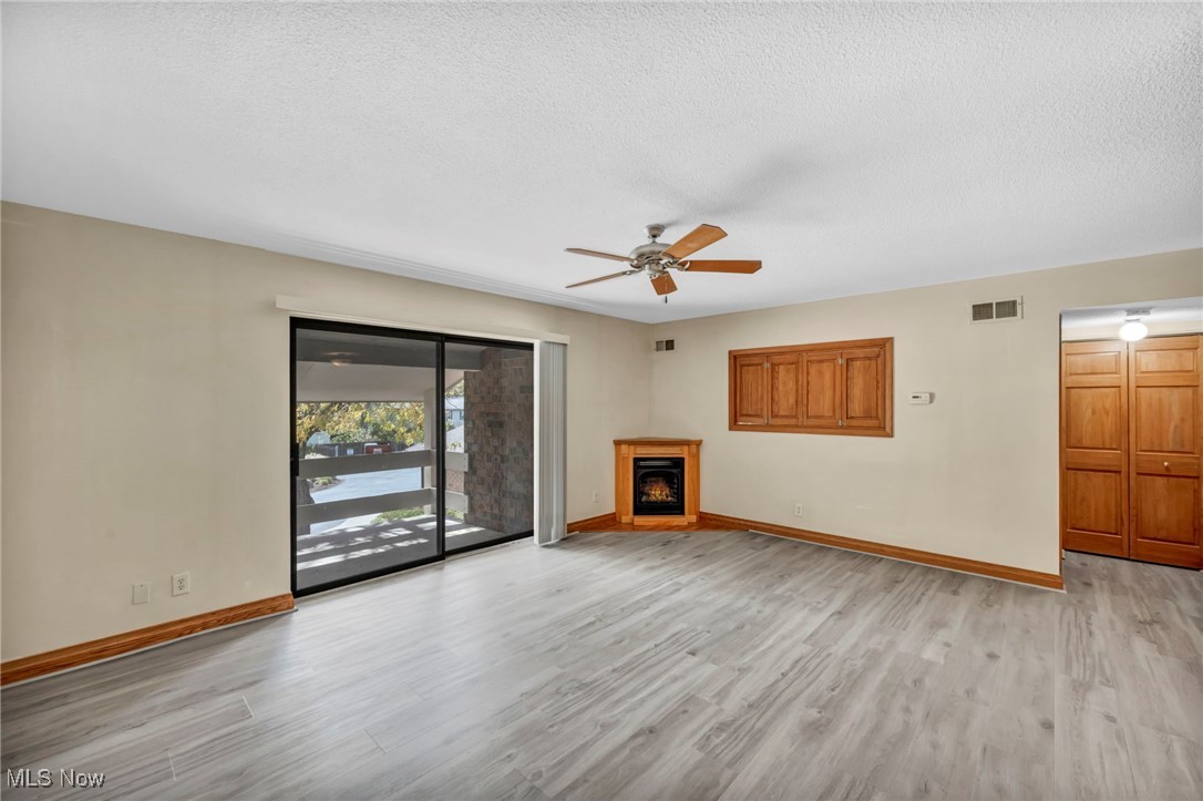 1263 Lost Nation Road, Unit 5 Willoughby, OH 44094 - Photo 7 of 26 Unfurnished living room with light wood-type flooring, a textured ceiling, and ceiling fan
