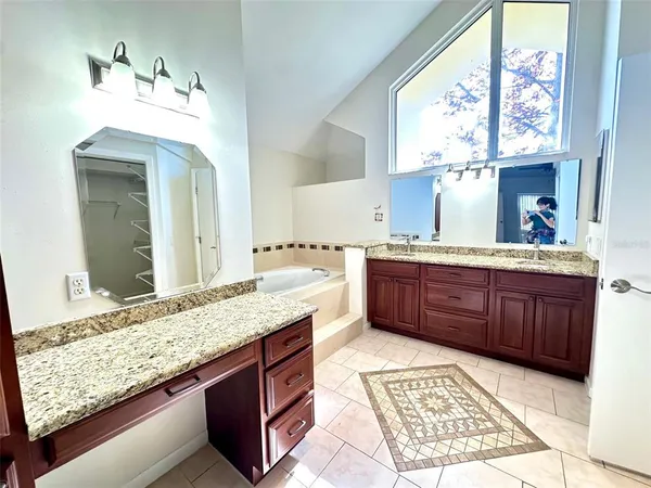 a bathroom with a granite countertop double vanity sink and a window