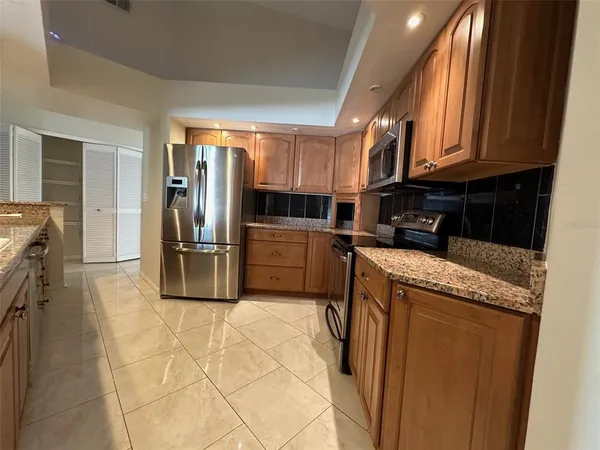 a kitchen with granite countertop a refrigerator and a stove top oven