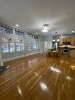 a view of a living room and kitchen with furniture wooden floor and chandelier