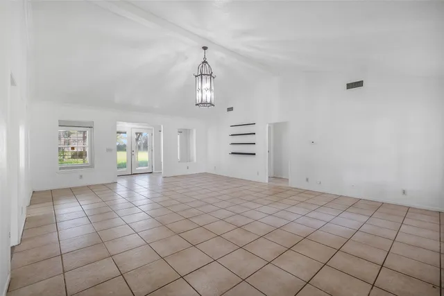 a view of empty room with kitchen and window