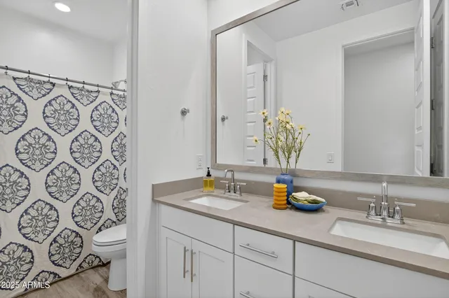 a bathroom with a granite countertop sink a toilet and a mirror