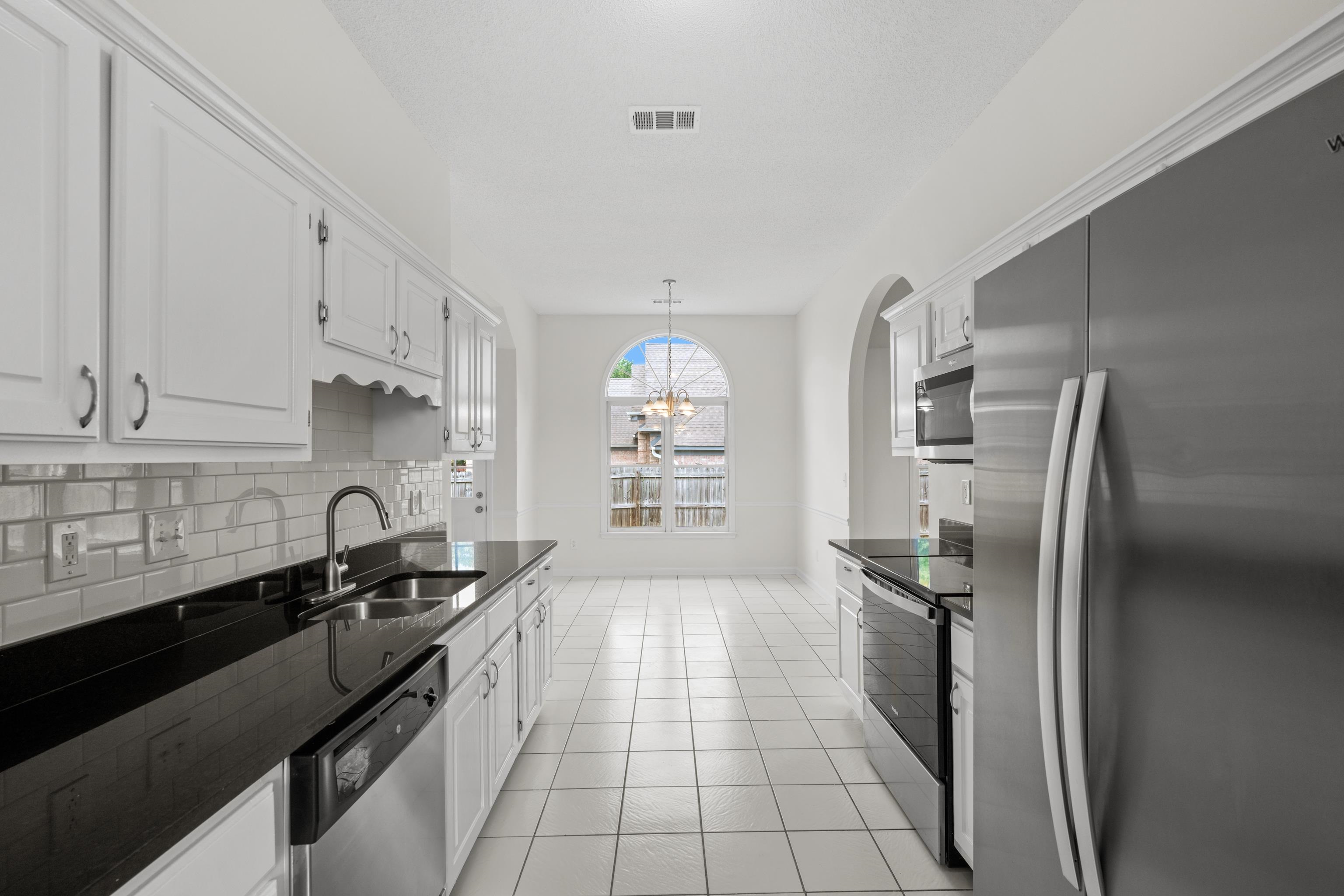 8016 Cale Falls Lane Bartlett, TN 38002 - Photo 14 of 37 a kitchen with granite countertop a refrigerator a sink a stove and cabinets