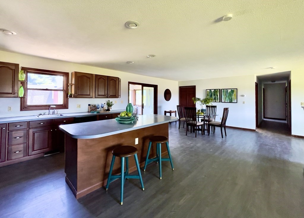 192 Hadley Road Sunderland, MA 01375 - Photo 9 of 30 a open kitchen with stainless steel appliances granite countertop a stove a refrigerator a kitchen island a dining table and chairs with wooden floor