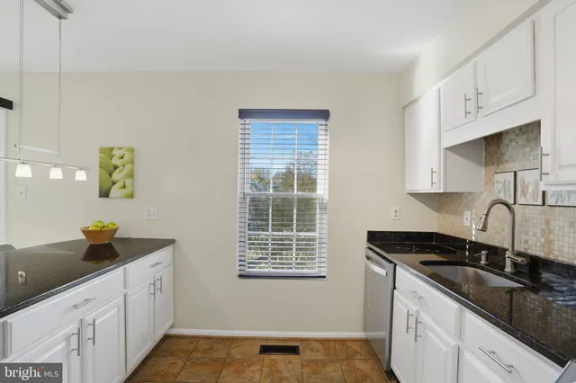a kitchen with granite countertop a sink a stove and cabinets