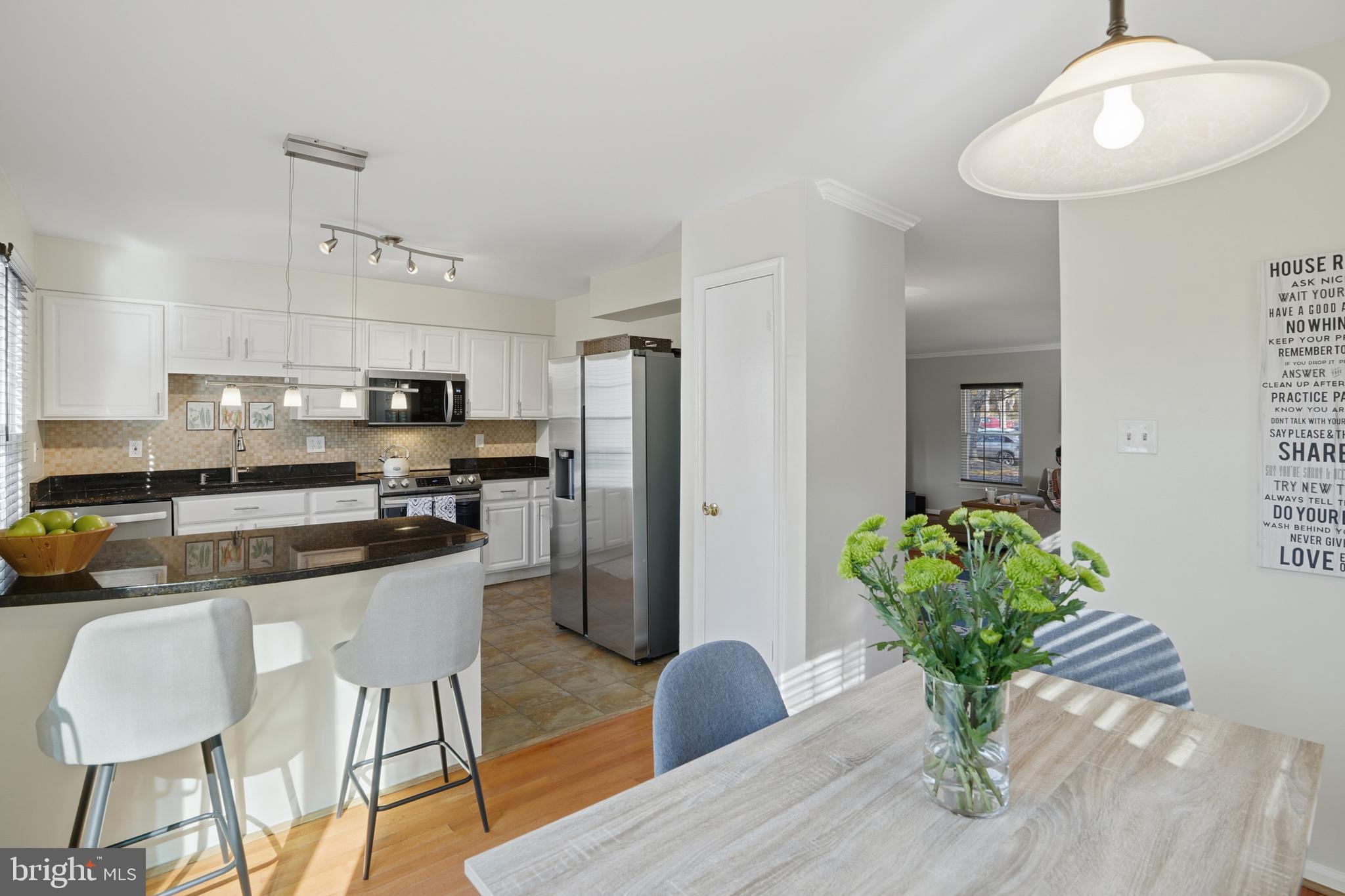 6172 Forest Creek Court Springfield, VA 22152 - Photo 19 of 42 a kitchen with stainless steel appliances granite countertop a refrigerator a sink dishwasher a dining table and chairs with wooden floor