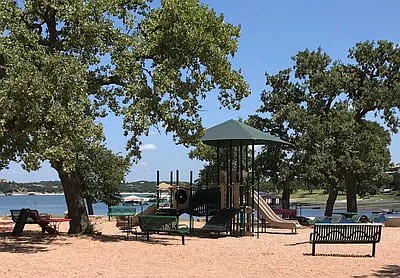 430 Summit Ridge Drive North Point Venture, TX 78645 - Photo 23 of 26 Community playground with mature trees and seating, offering endless outdoor enjoyment.
