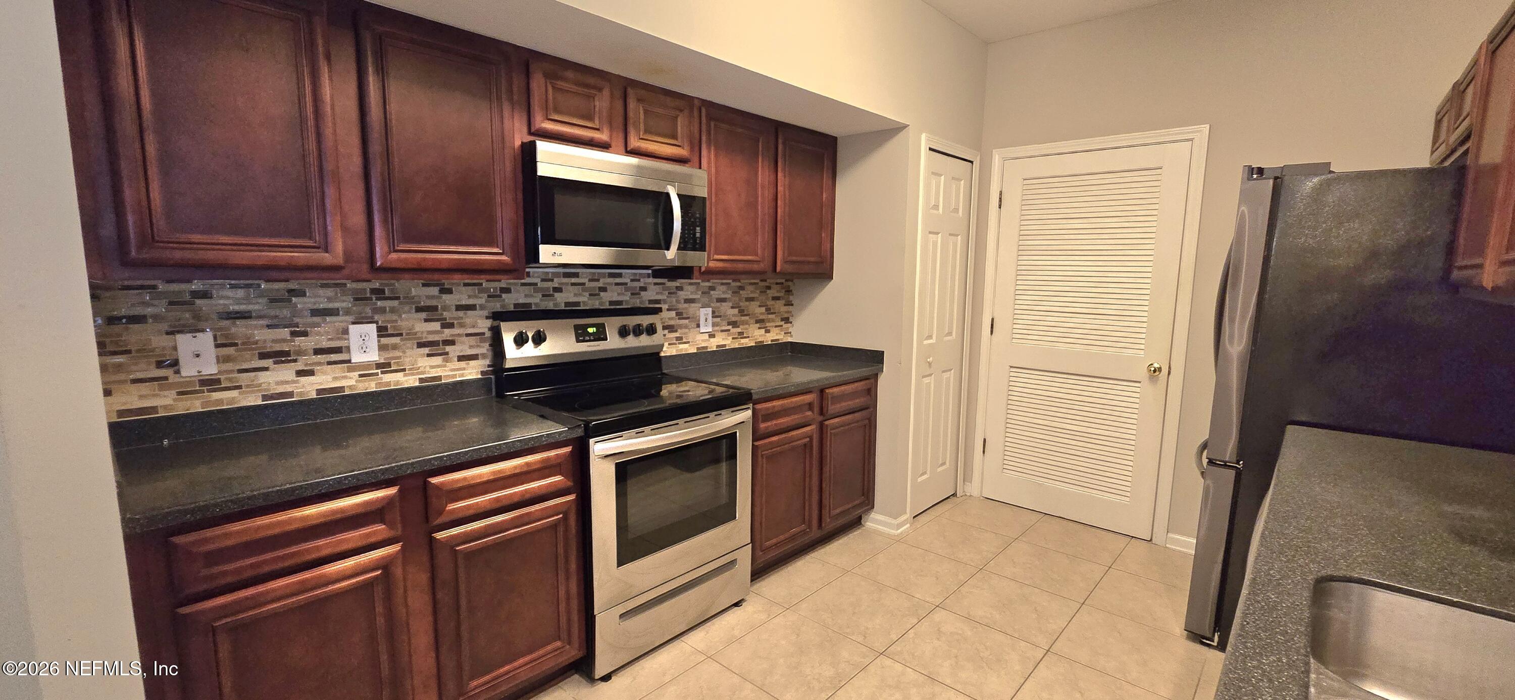 8226 Green Parrot Road, Unit 206 Jacksonville, FL 32256 - Photo 17 of 20 a kitchen with stainless steel appliances granite countertop wooden cabinets a stove top oven a sink and dishwasher