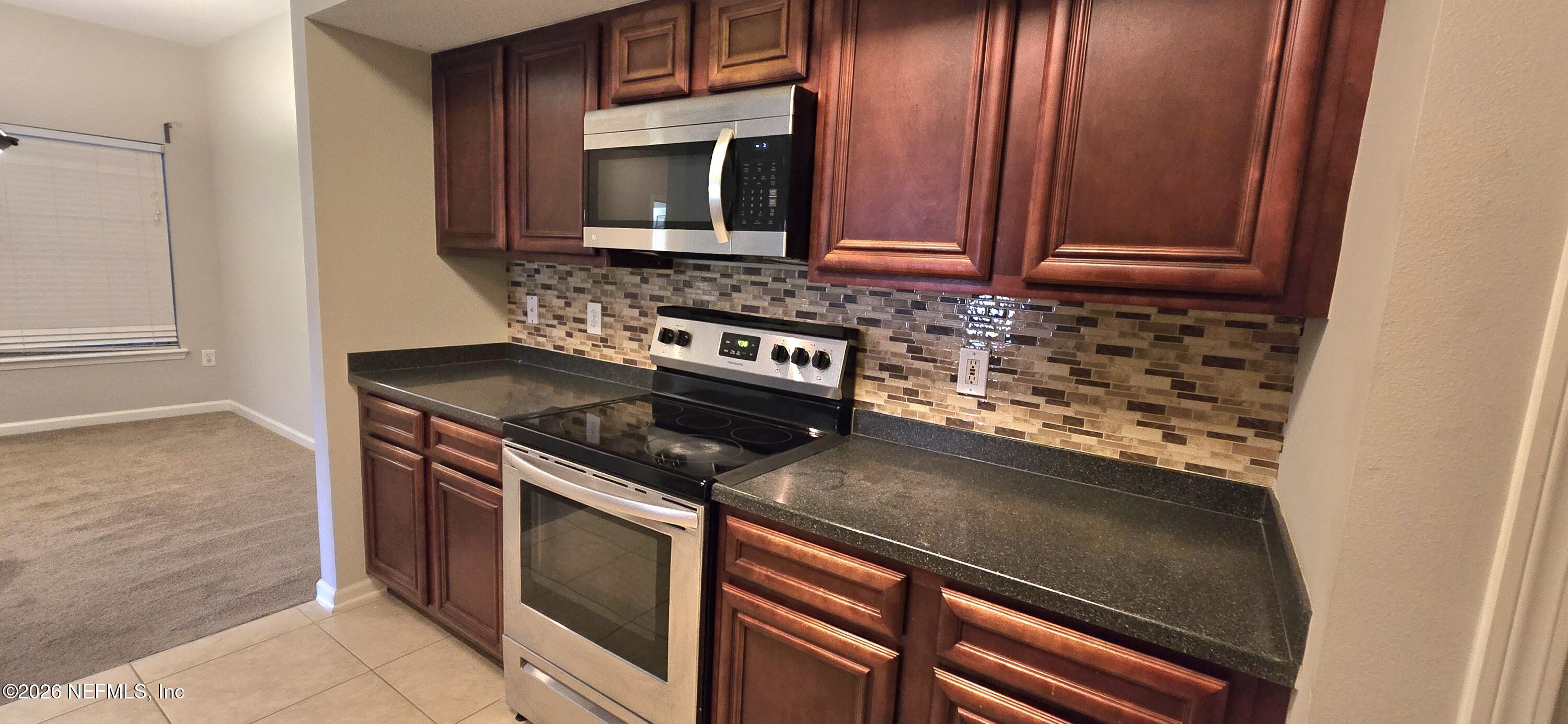 8226 Green Parrot Road, Unit 206 Jacksonville, FL 32256 - Photo 19 of 20 a kitchen with granite countertop a stove microwave and sink