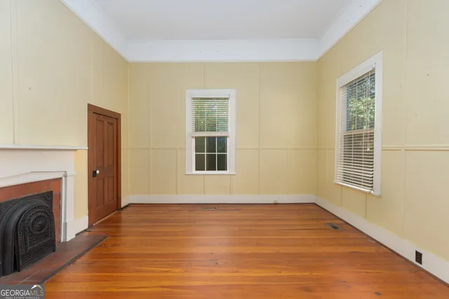 a view of an empty room with wooden floor and a window