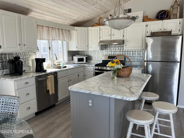 a kitchen with stainless steel appliances granite countertop a sink a stove a refrigerator a stove a dining table and chairs