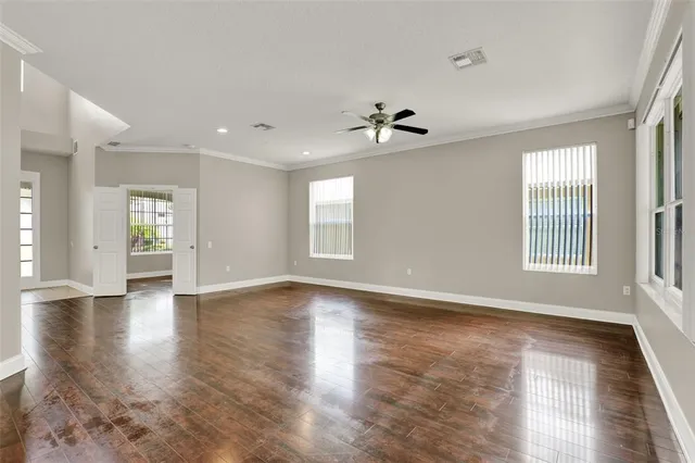 a view of an empty room with a window and wooden floor
