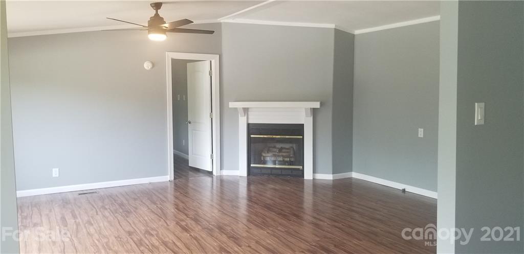 4880 Crystal Creek Road Morganton, NC 28655 - Photo 18 of 26 an empty room with wooden floor a ceiling fan a kitchen and a window