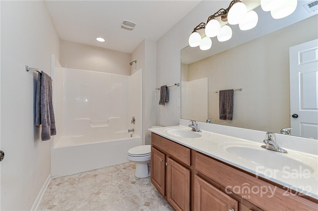 7179 Meyer Road Fort Mill, SC 29715 - Photo 39 of 47 a bathroom with a granite countertop sink a toilet a mirror a bathtub and shower