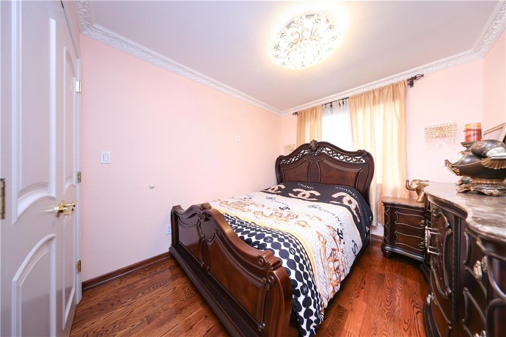 2568 East 2nd Street Brooklyn, NY 11223 - Photo 26 of 41 a bedroom with a bed and a chandelier