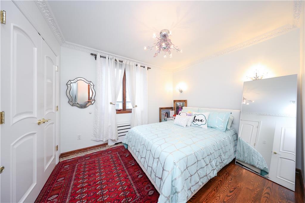 2568 East 2nd Street Brooklyn, NY 11223 - Photo 28 of 41 a bedroom with a bed and a chandelier