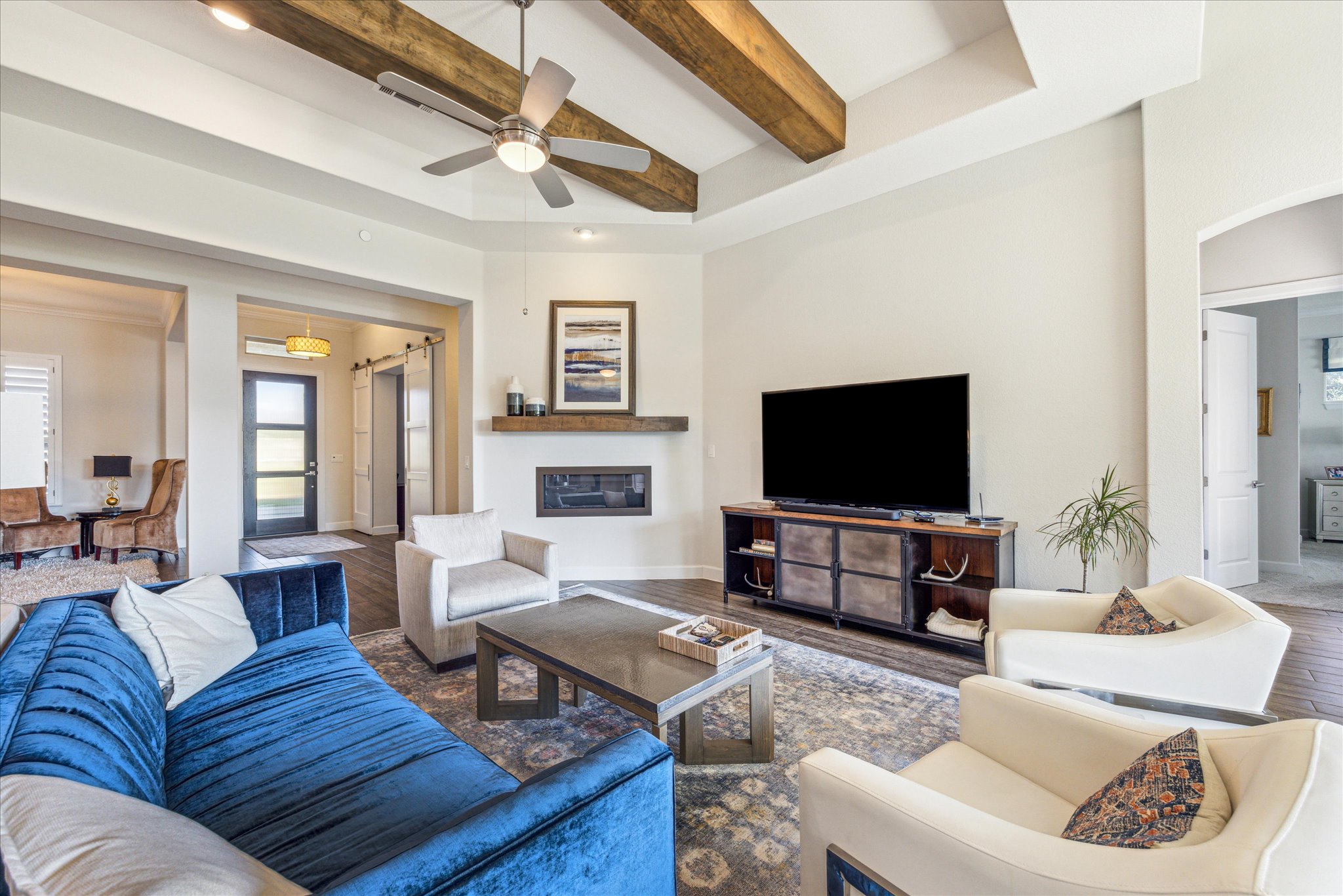 9600 Chamois Way Austin, TX 78736 - Photo 2 of 14 Living area featuring beamed ceiling, wood finished floors, ceiling fan, arched walkways, and a glass covered fireplace