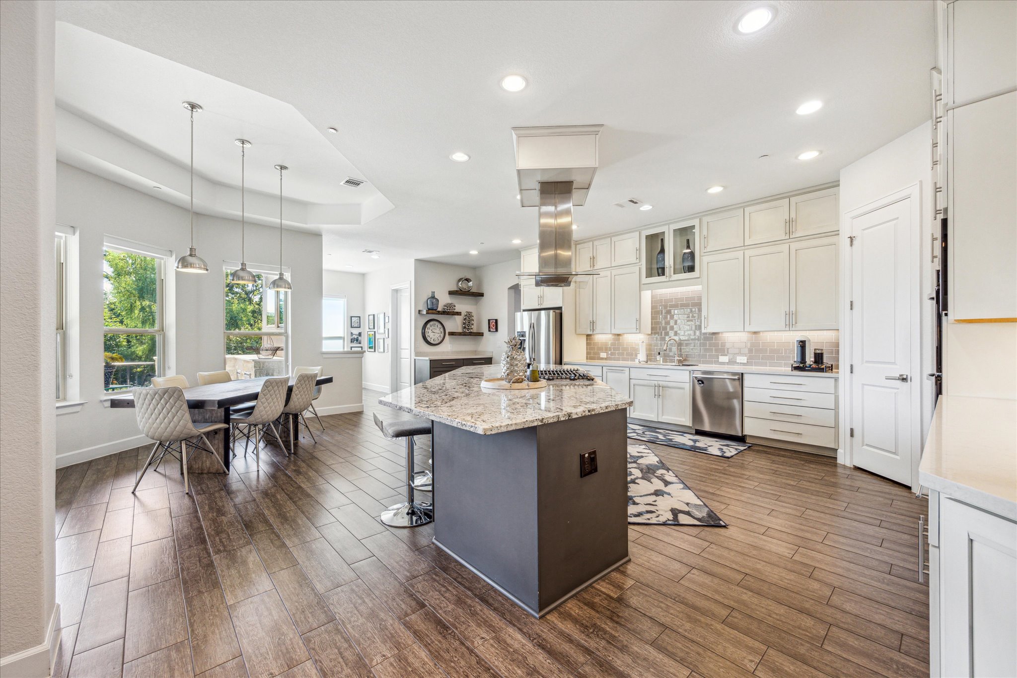 9600 Chamois Way Austin, TX 78736 - Photo 4 of 14 Dual tone kitchen featuring a center island, light stone countertops, dual tone cabinetry, dark wood-type flooring, and decorative backsplash