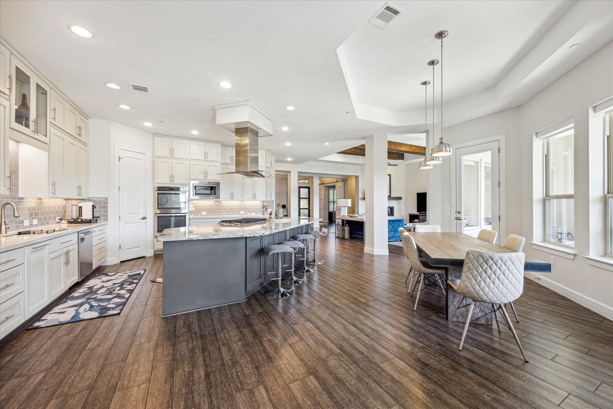 9600 Chamois Way Austin, TX 78736 - Photo 5 of 14 Kitchen with light stone countertops, two tone color scheme, a large island with sink, glass insert cabinets, and decorative backsplash