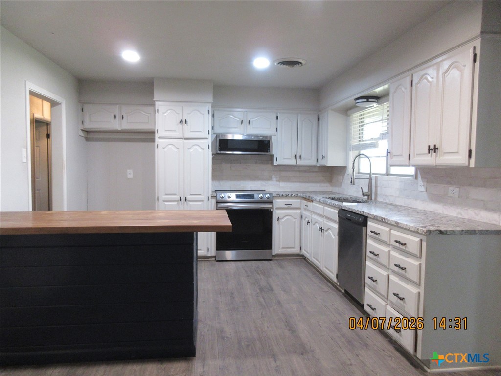 506 East Loop 121 Belton, TX 76513 - Photo 6 of 29 a kitchen with a sink dishwasher a stove a refrigerator and white cabinets