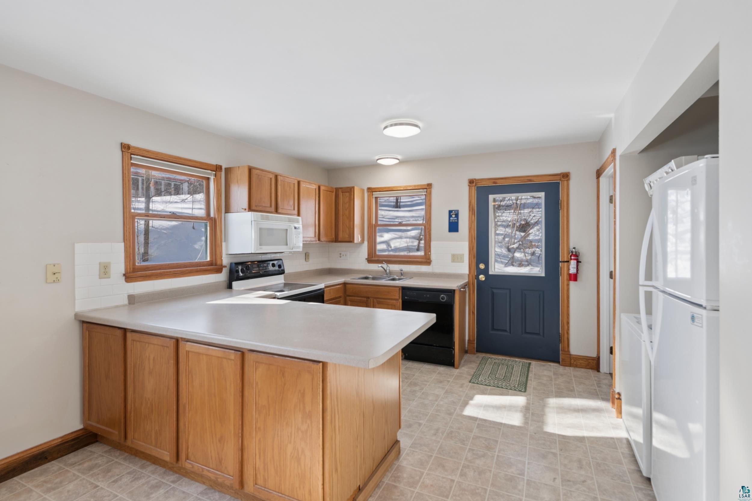 33 South 4th Street Bayfield, WI 54814 - Photo 13 of 29 Kitchen featuring a peninsula, light countertops, white appliances, wood finish cabinetry, and tasteful backsplash