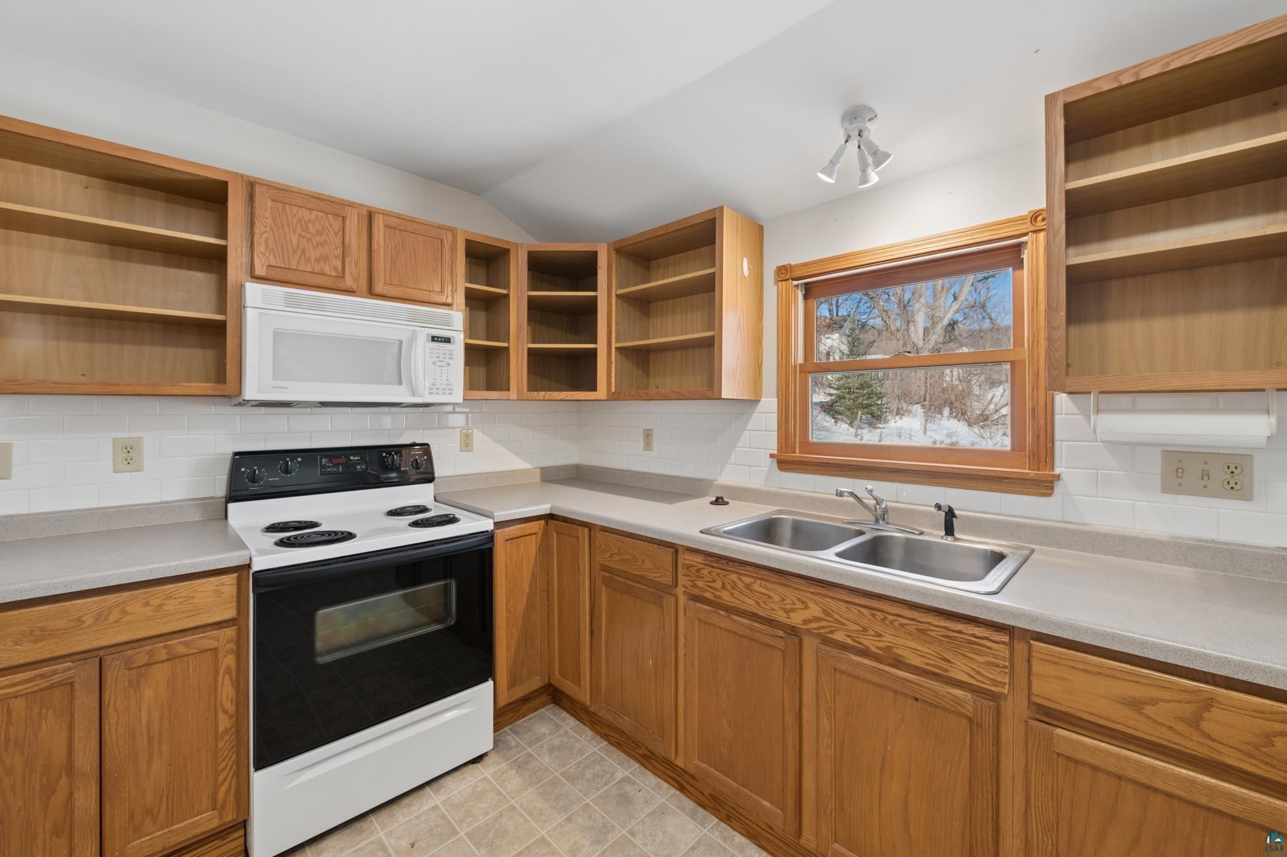 33 South 4th Street Bayfield, WI 54814 - Photo 18 of 29 Kitchen featuring open shelves, range with electric cooktop, white microwave, backsplash, and lofted ceiling