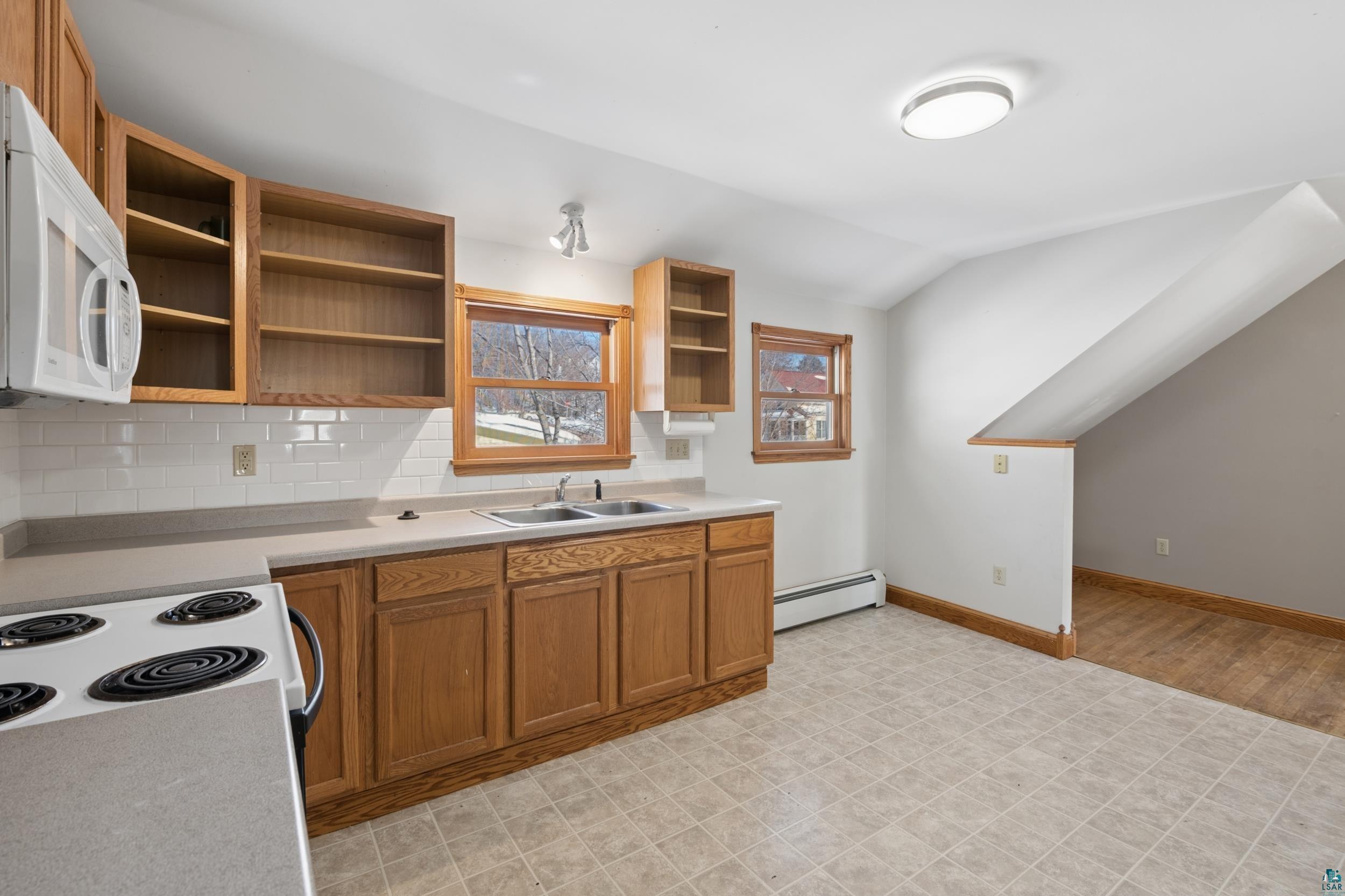 33 South 4th Street Bayfield, WI 54814 - Photo 19 of 29 Kitchen with white appliances, decorative backsplash, wood finish cabinets, light countertops, and lofted ceiling