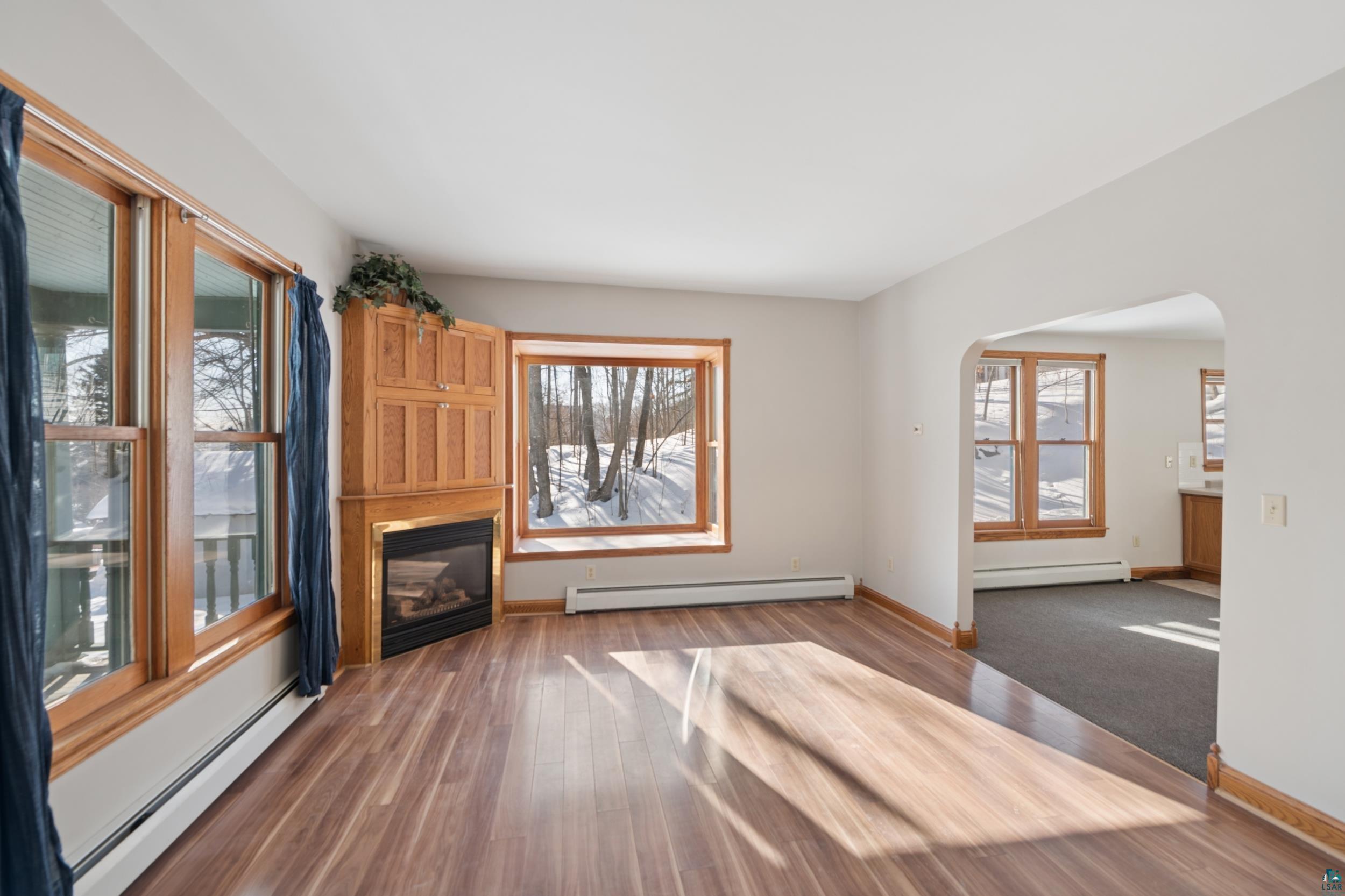 33 South 4th Street Bayfield, WI 54814 - Photo 6 of 29 Unfurnished living room featuring a baseboard heating unit, dark wood-type flooring, and a glass covered fireplace