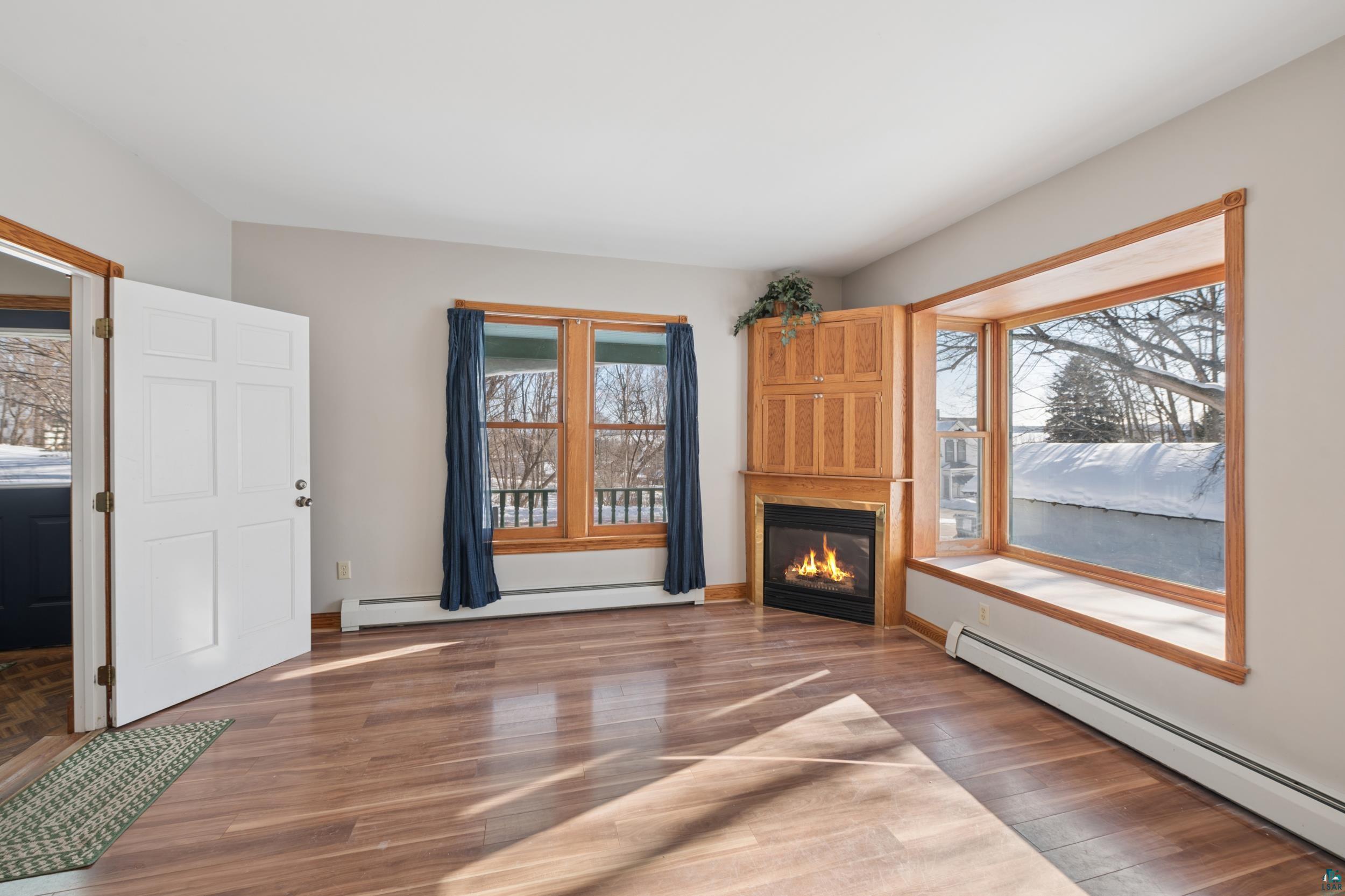 33 South 4th Street Bayfield, WI 54814 - Photo 7 of 29 Unfurnished living room with a baseboard radiator, wood finished floors, and a glass covered fireplace
